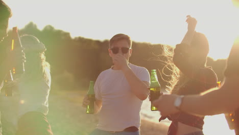 La-Compañía-De-Mejores-Amigos-Mueve-Sus-Cuerpos-Jóvenes-Bailando-Con-Cerveza-En-La-Calurosa-Fiesta-De-Verano-En-La-Playa.-Los-Jóvenes-Disfrutan-De-La-Fiesta-De-Verano-Al-Aire-Libre.